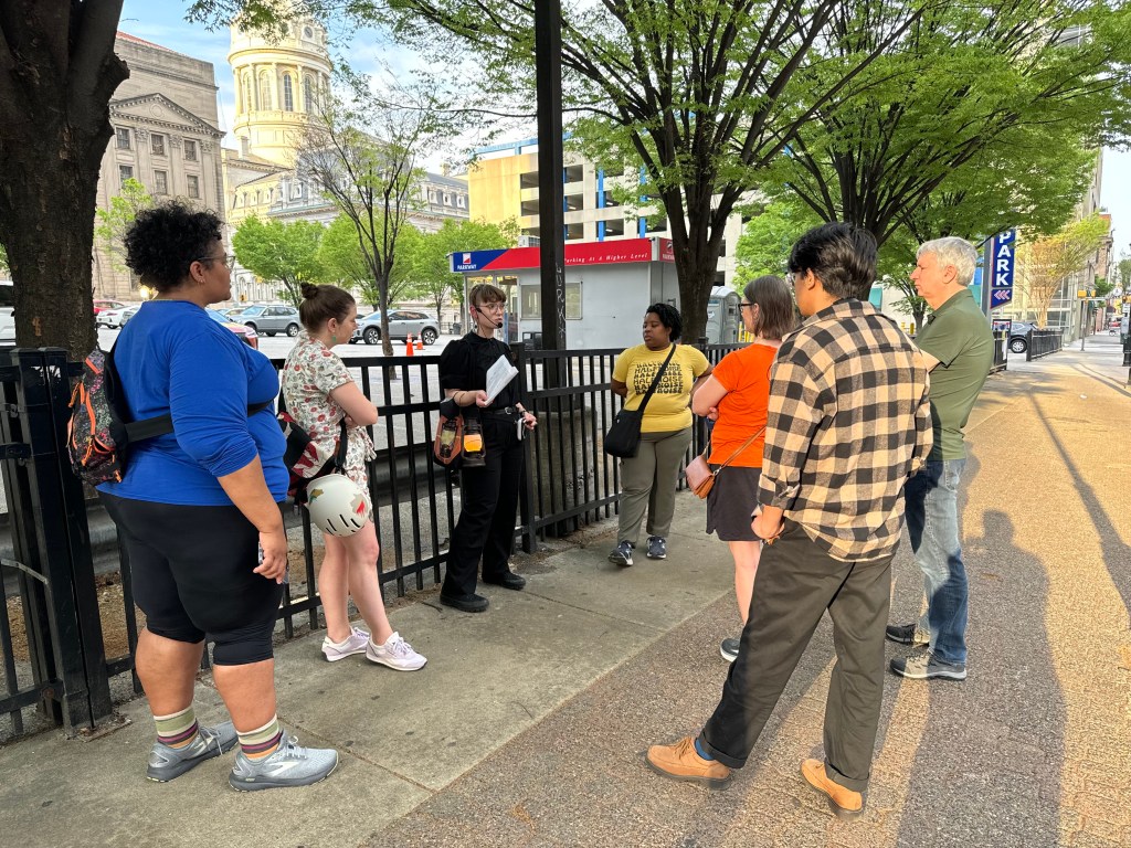 Tour group standing around a tour guide on Baltimore Street in downtown Baltimore.